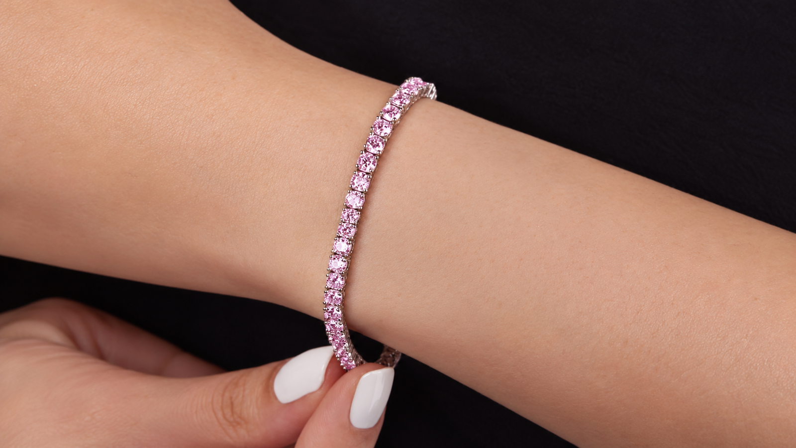Wrist wearing a pink diamond tennis bracelet, showcasing affordable luxury jewelry for an elegant everyday look.