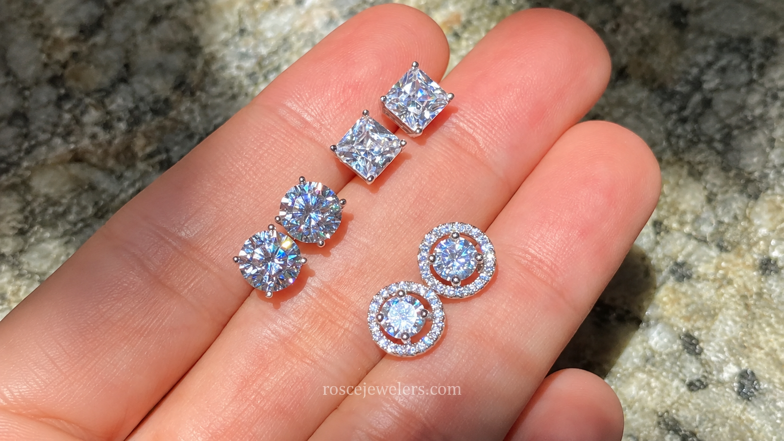 a hand holding 3 different sets of diamond studs