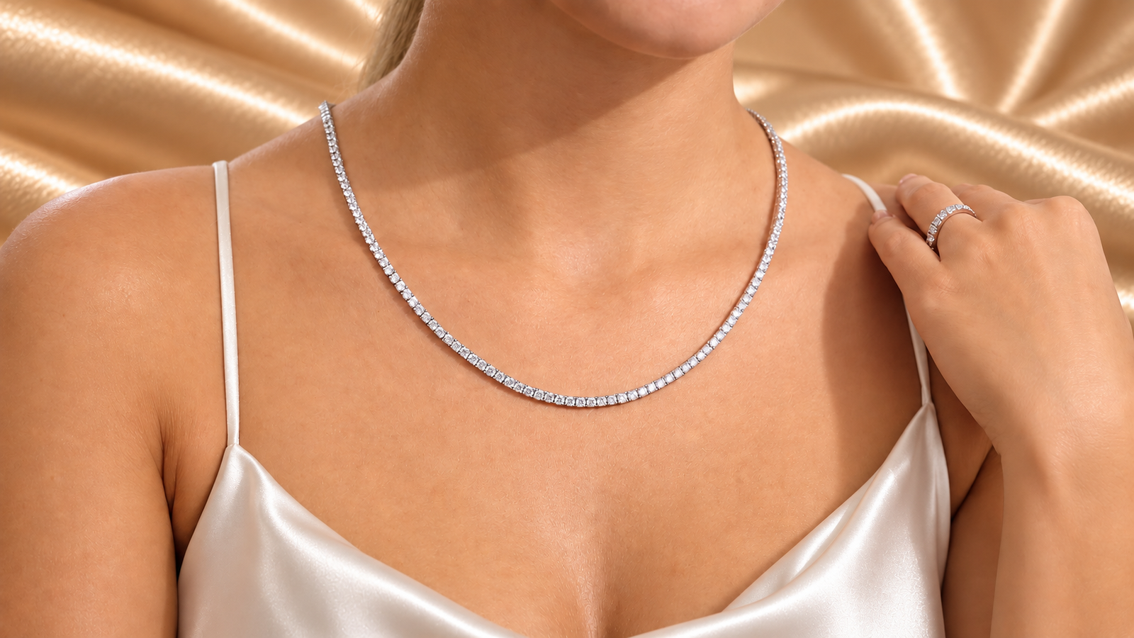 Woman’s neck and upper shoulder wearing a tennis necklace and diamond ring, showcasing affordable luxury jewelry.