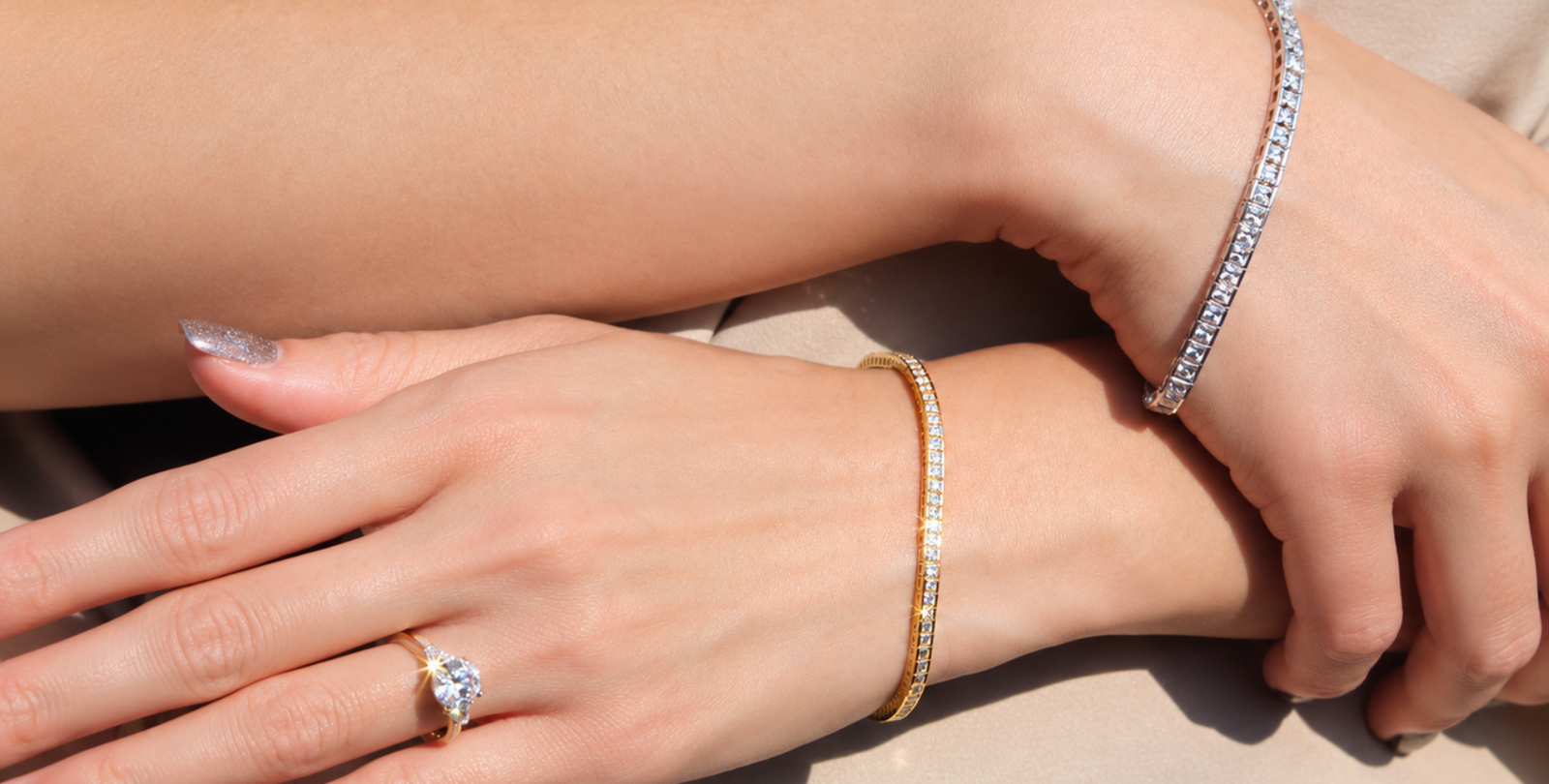 Two hands wearing white gold and yellow gold tennis bracelets, showcasing affordable luxury jewelry in contrasting metal tones.