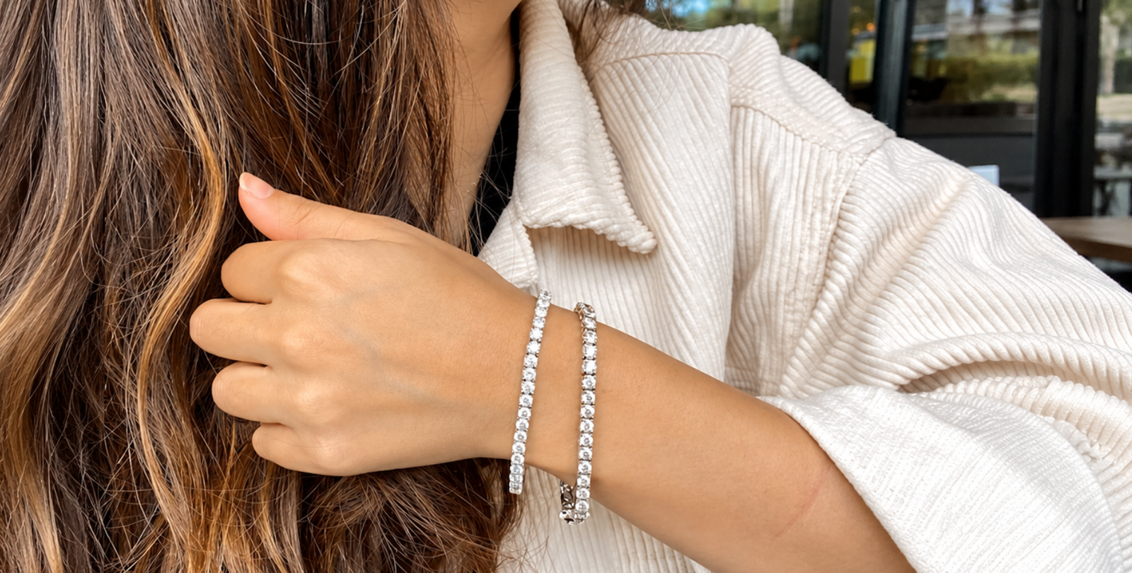Woman showcasing her wrist adorned with elegant tennis bracelets, highlighting affordable luxury jewelry.